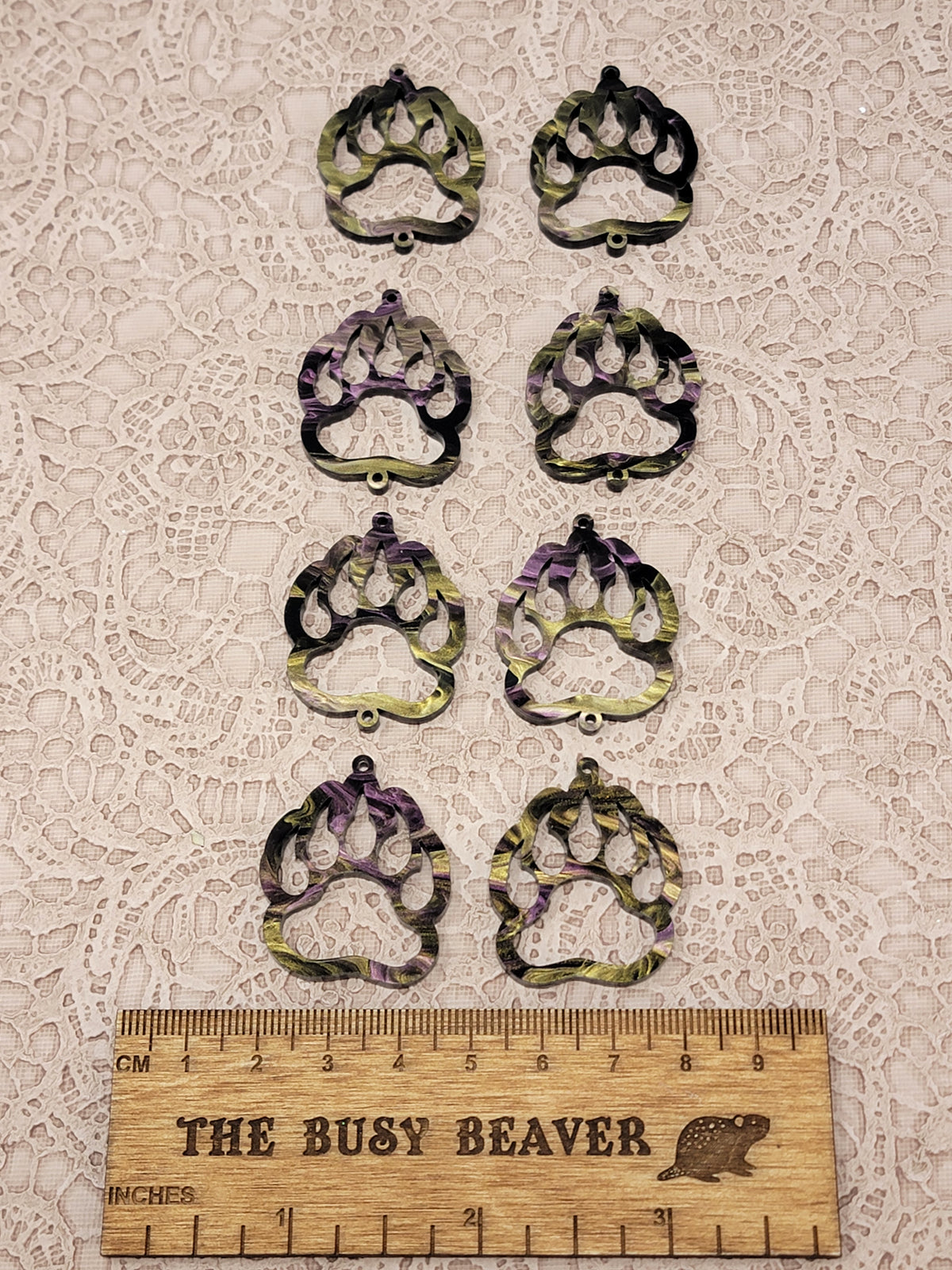 Two sets of four graduated acrylic open bear paws in gold/purple marble, beside a ruler