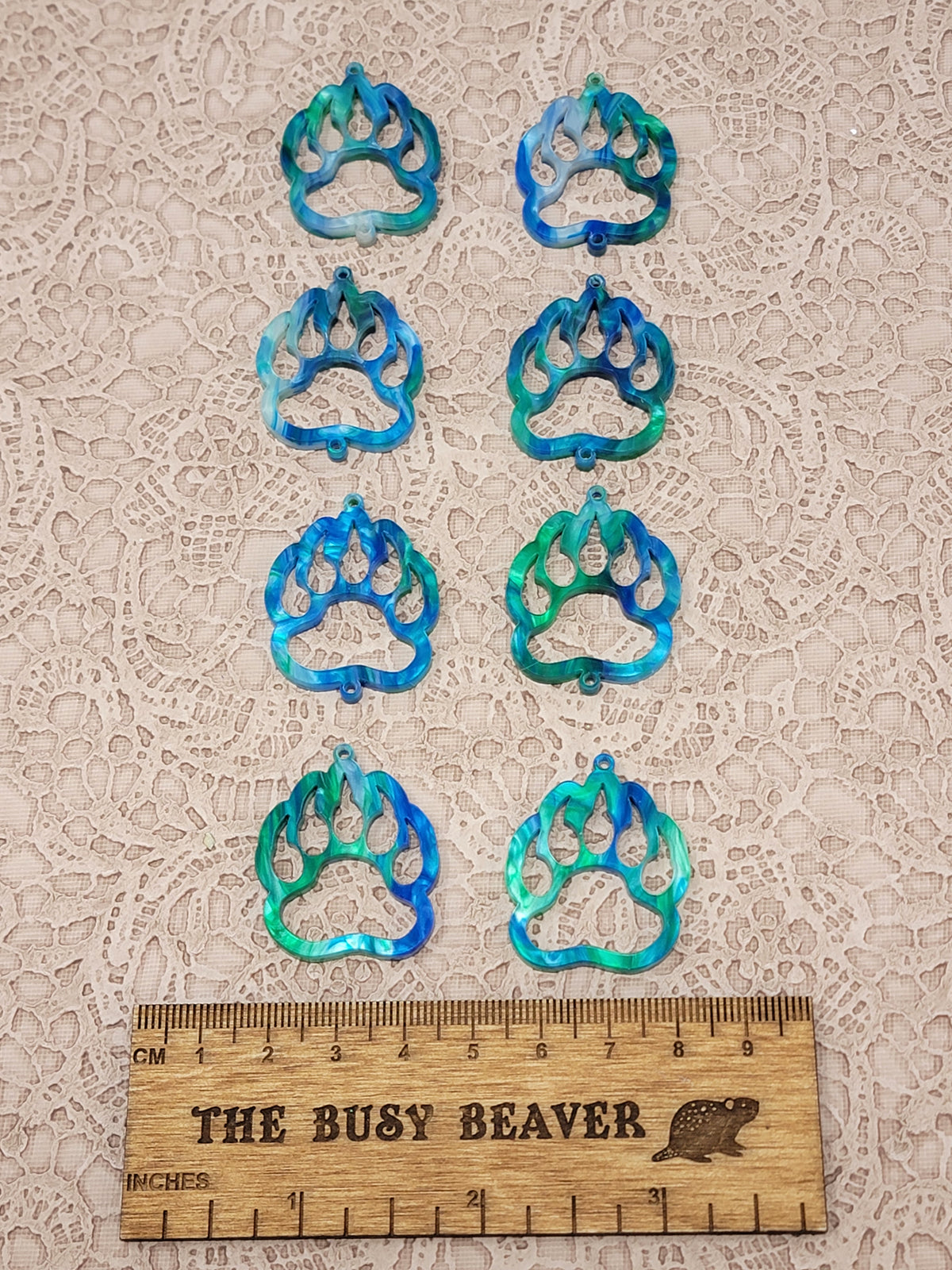 Two sets of four graduated acrylic open bear paws in blue/green marble, beside a ruler