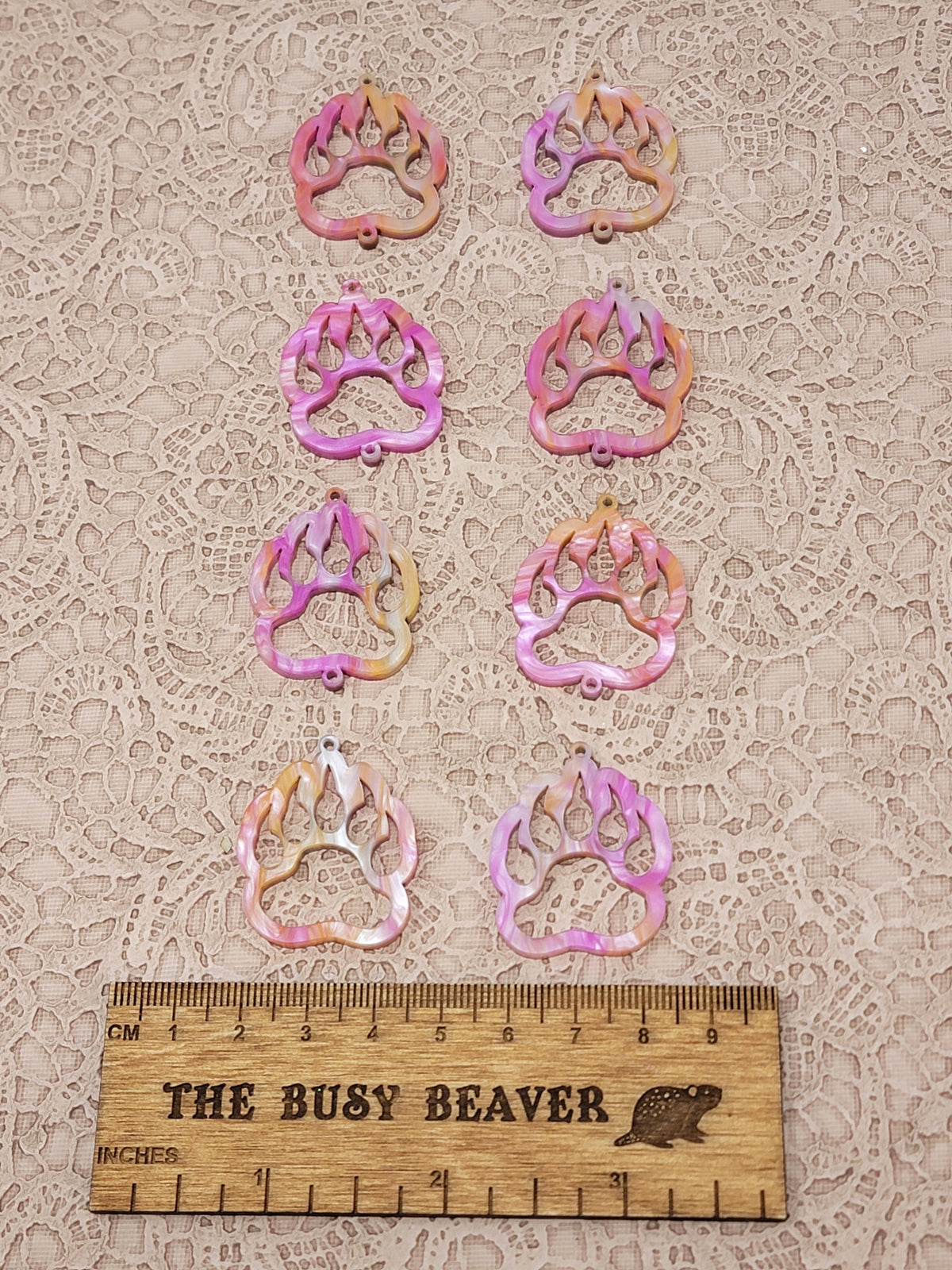 Two sets of four graduated acrylic open bear paws in pink/orange marble, beside a ruler