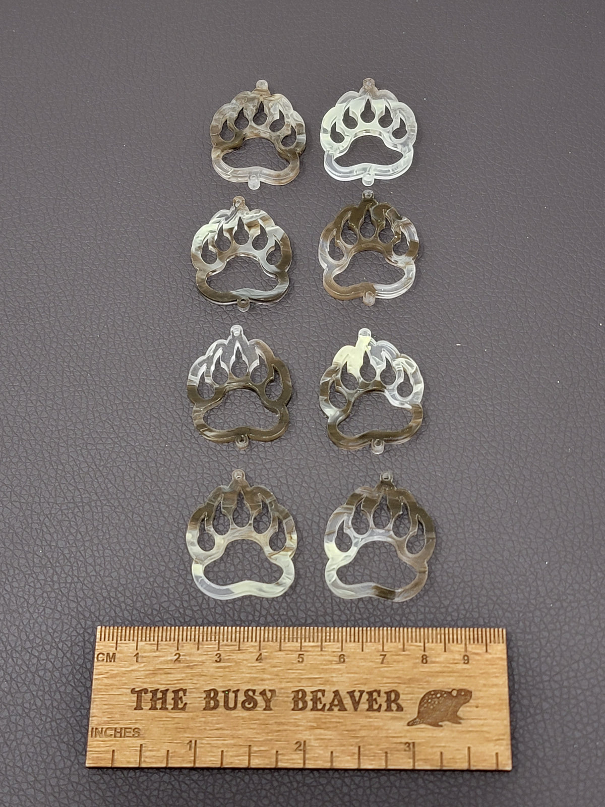 Two sets of four graduated acrylic open bear paws in cream/brown marble, beside a ruler