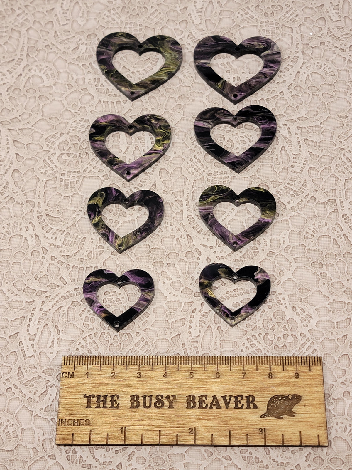 Two sets of four graduated acrylic open hearts in black/purple/gold marble, beside a ruler