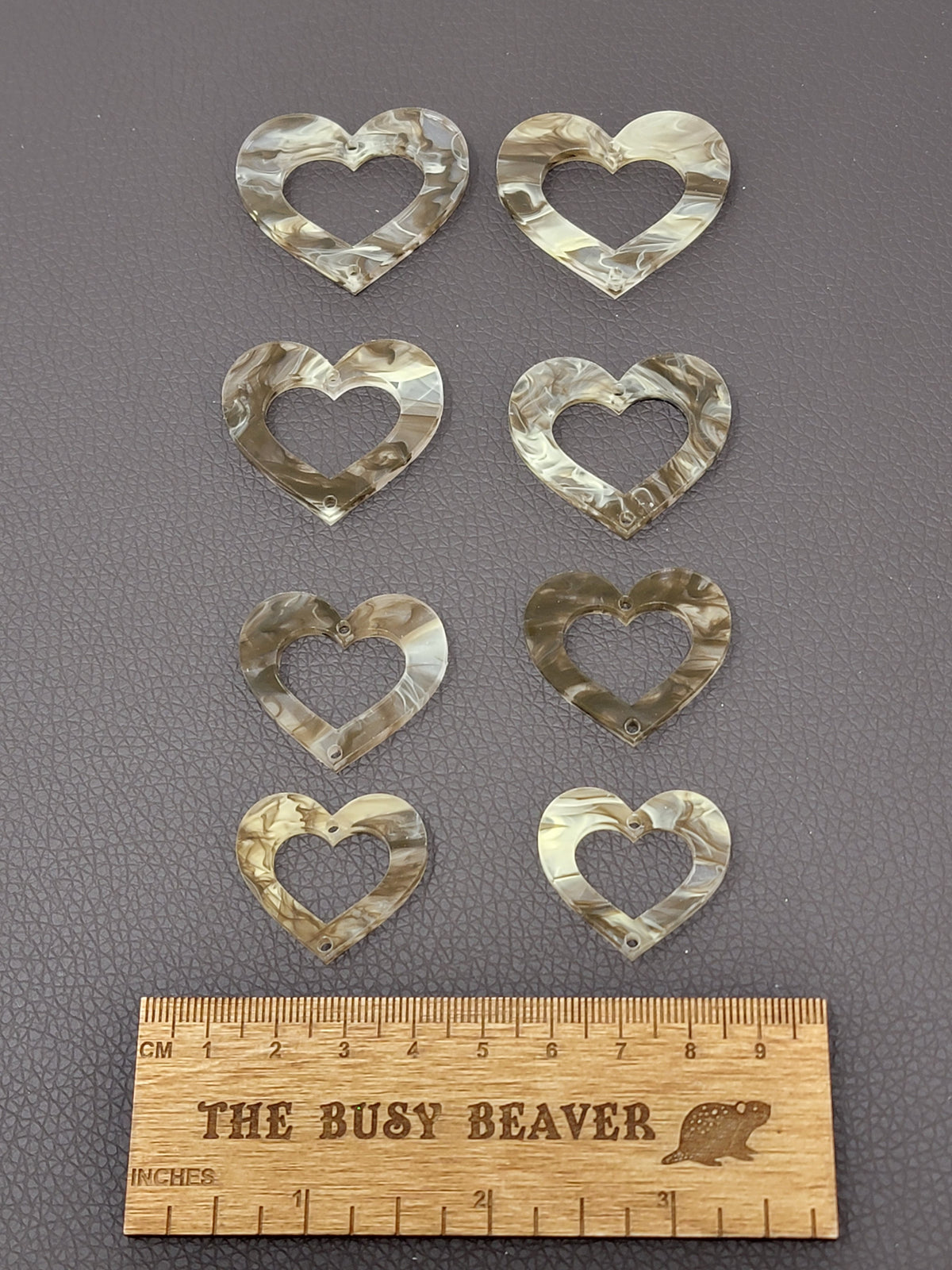 Two sets of four graduated acrylic open hearts in cream/brown marble, beside a ruler