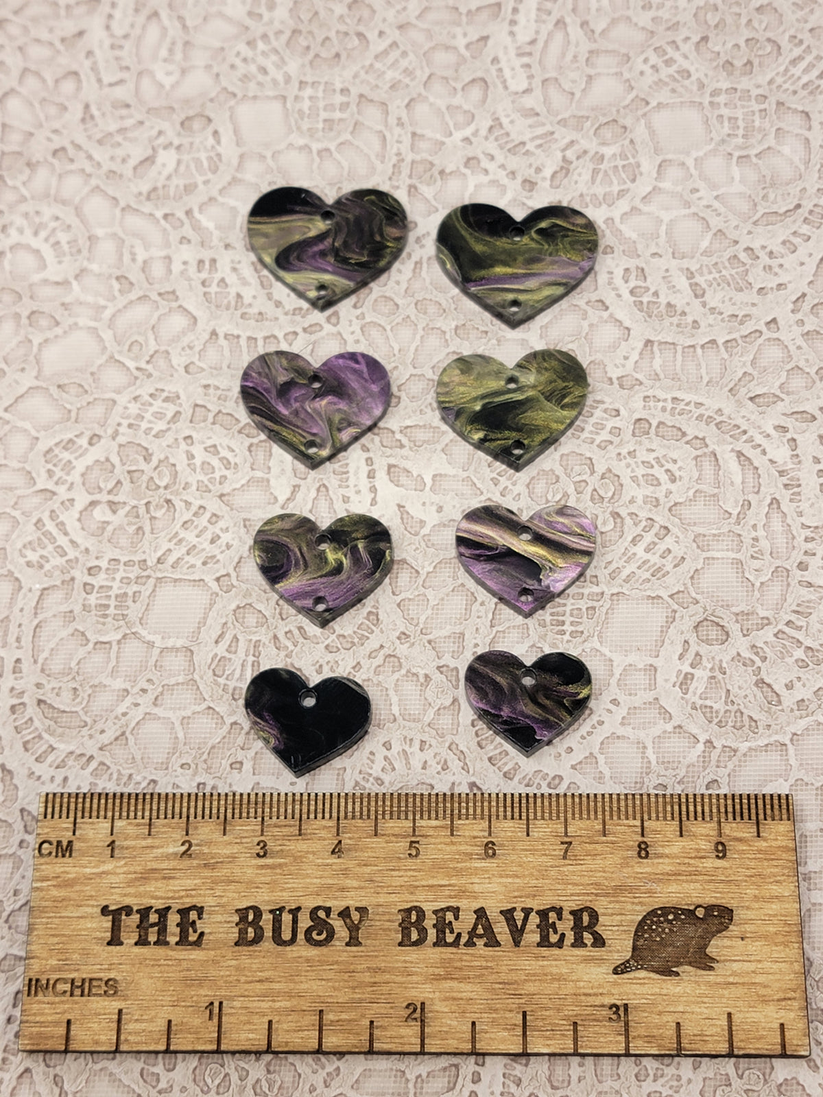 Two sets of four graduated acrylic hearts in purple/gold/black, beside a ruler