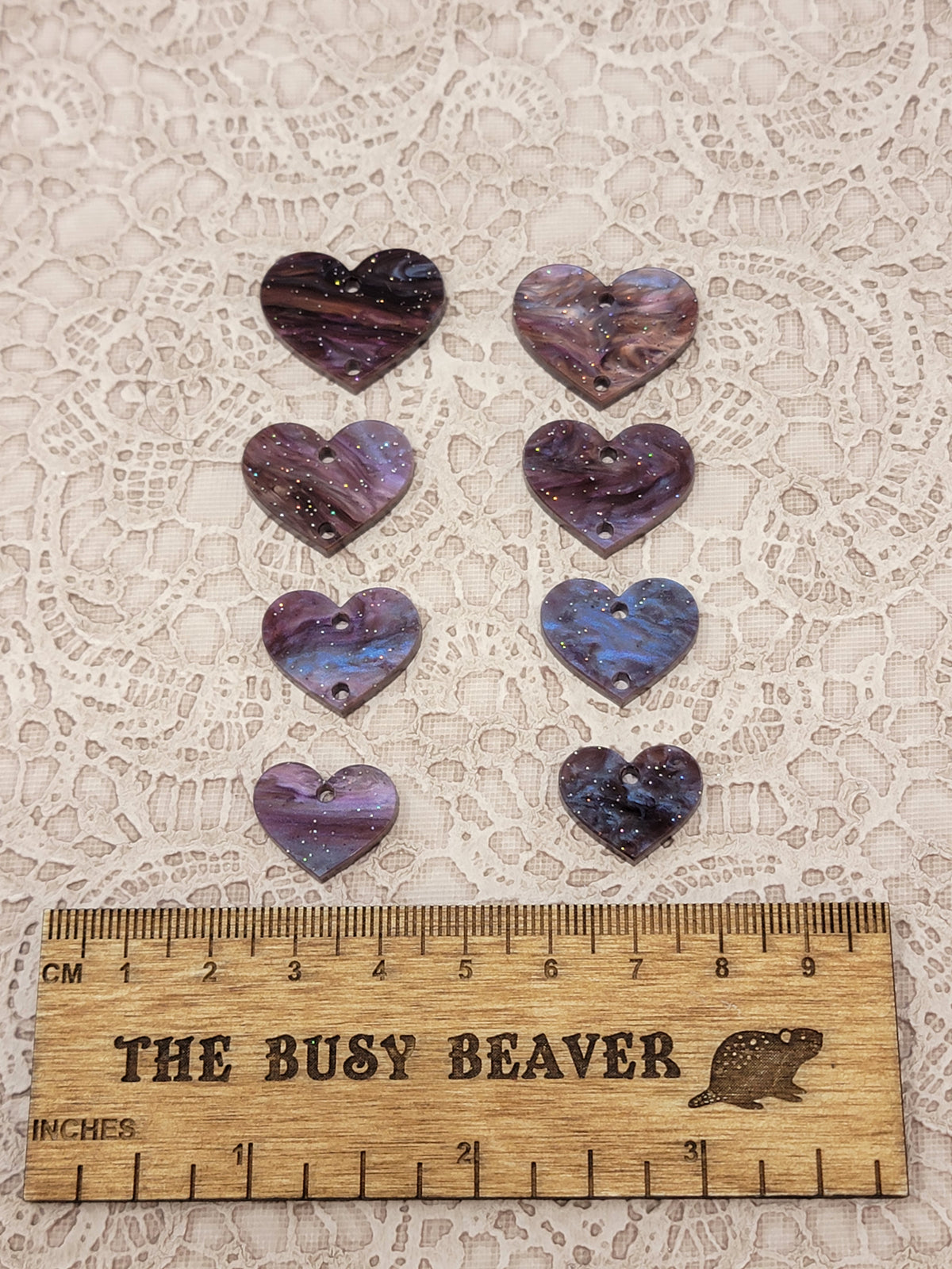 Two sets of four graduated acrylic hearts in brown marble glitter, beside a ruler