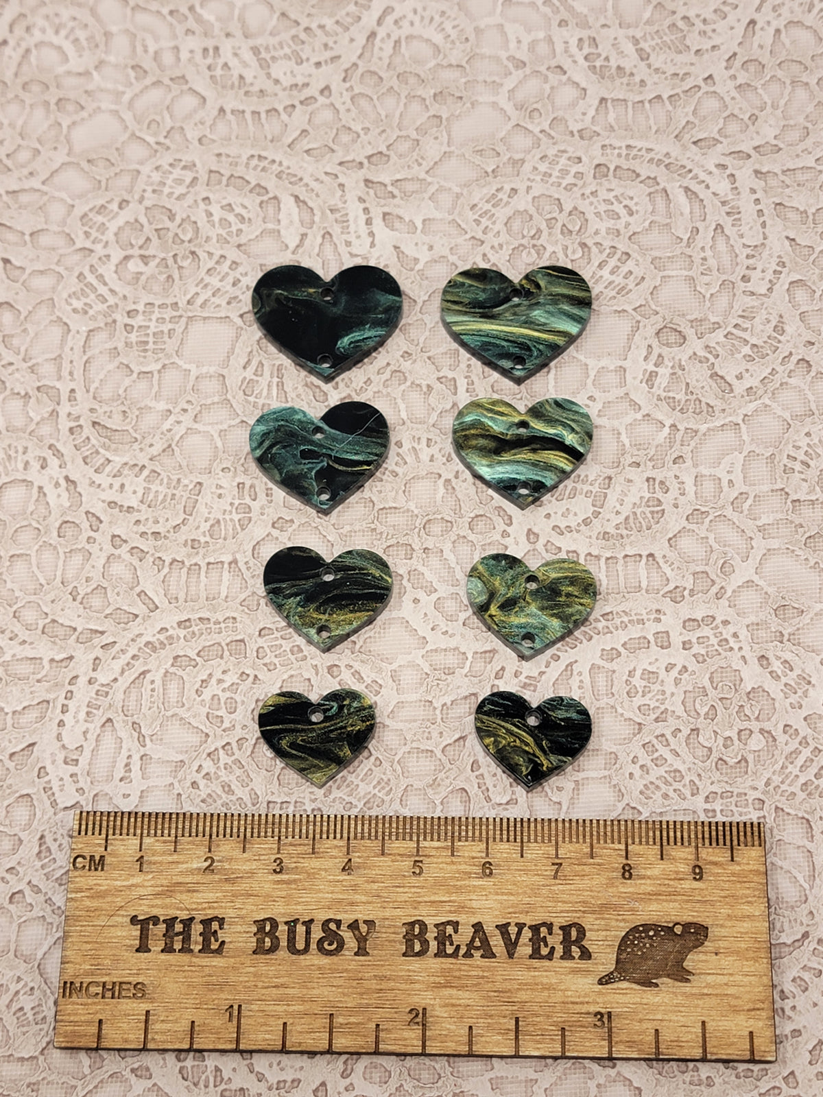 Two sets of four graduated acrylic hearts in black/gold/green marble, beside a ruler