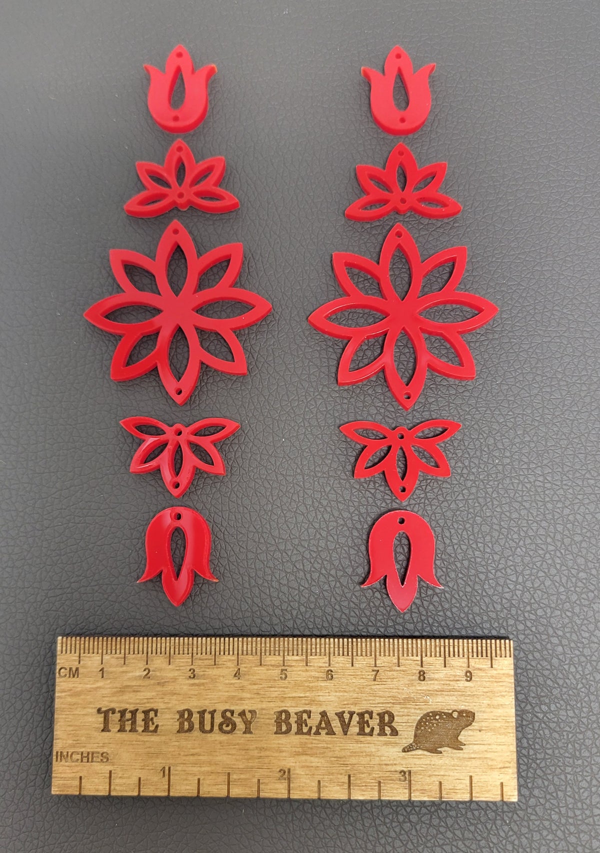Two 5-tier acrylic flower earring sets in red, laid out top to bottom beside a ruler
