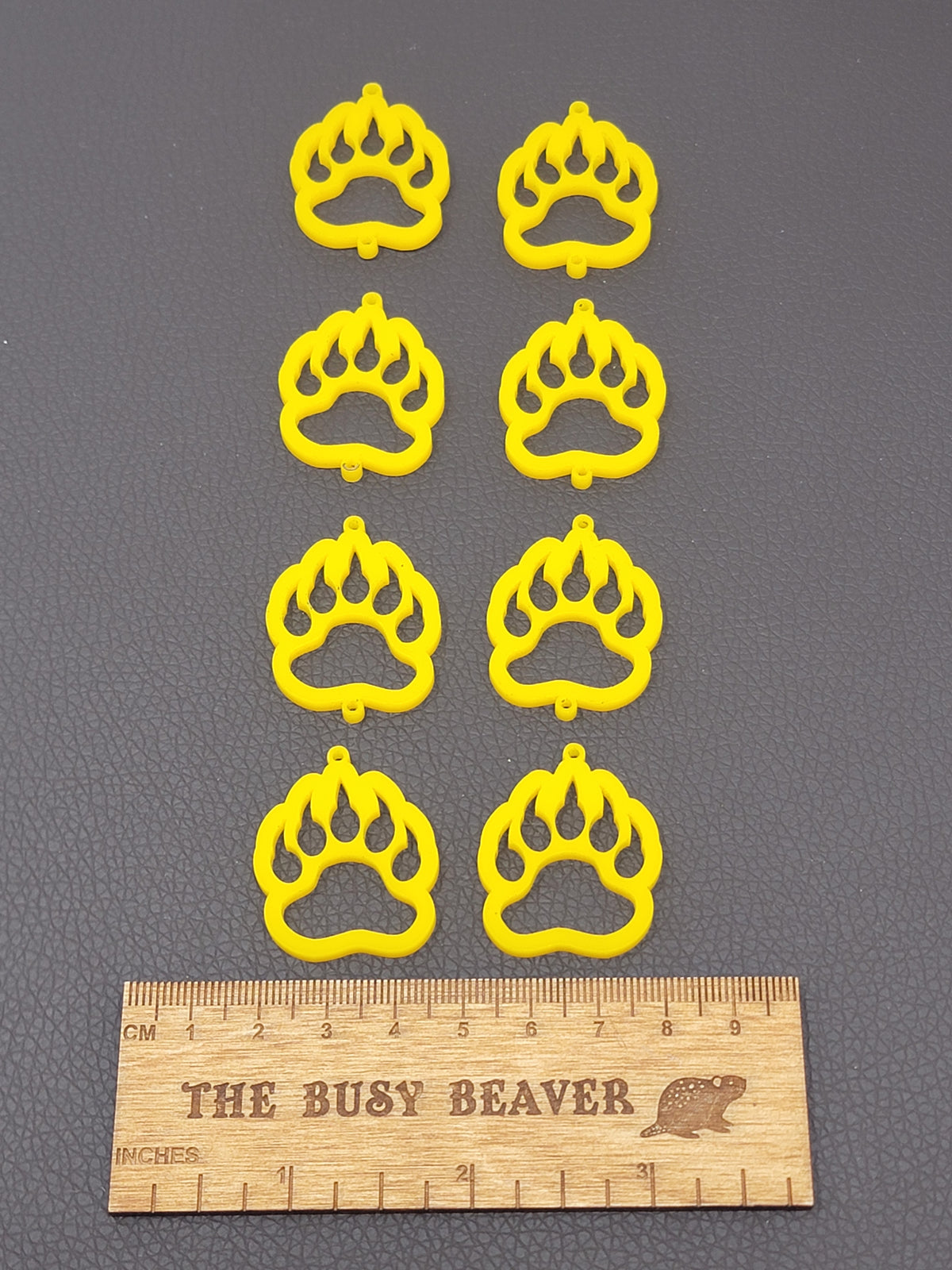 Two sets of four graduated acrylic open bear paws in yellow, beside a ruler