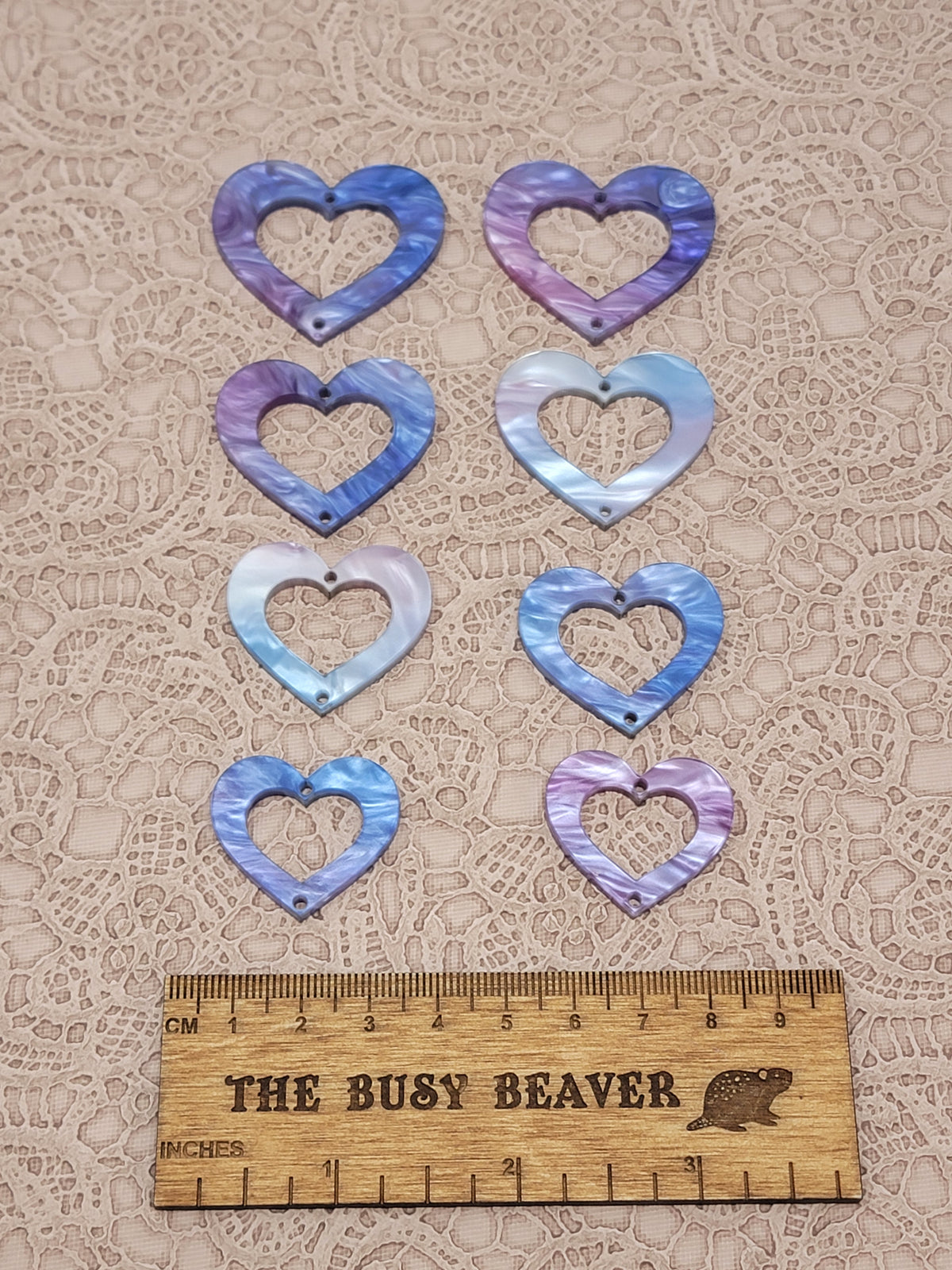 Two sets of four graduated acrylic open hearts in fuchsia/blue marble, beside a ruler