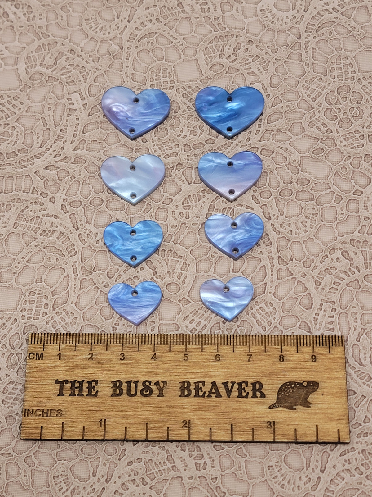 Two sets of four graduated acrylic hearts in fuchsia/blue marble, beside a ruler