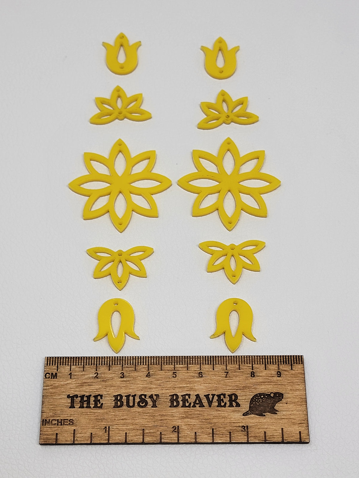 Two 5-tier acrylic flower earring sets in yellow, laid out top to bottom beside a ruler