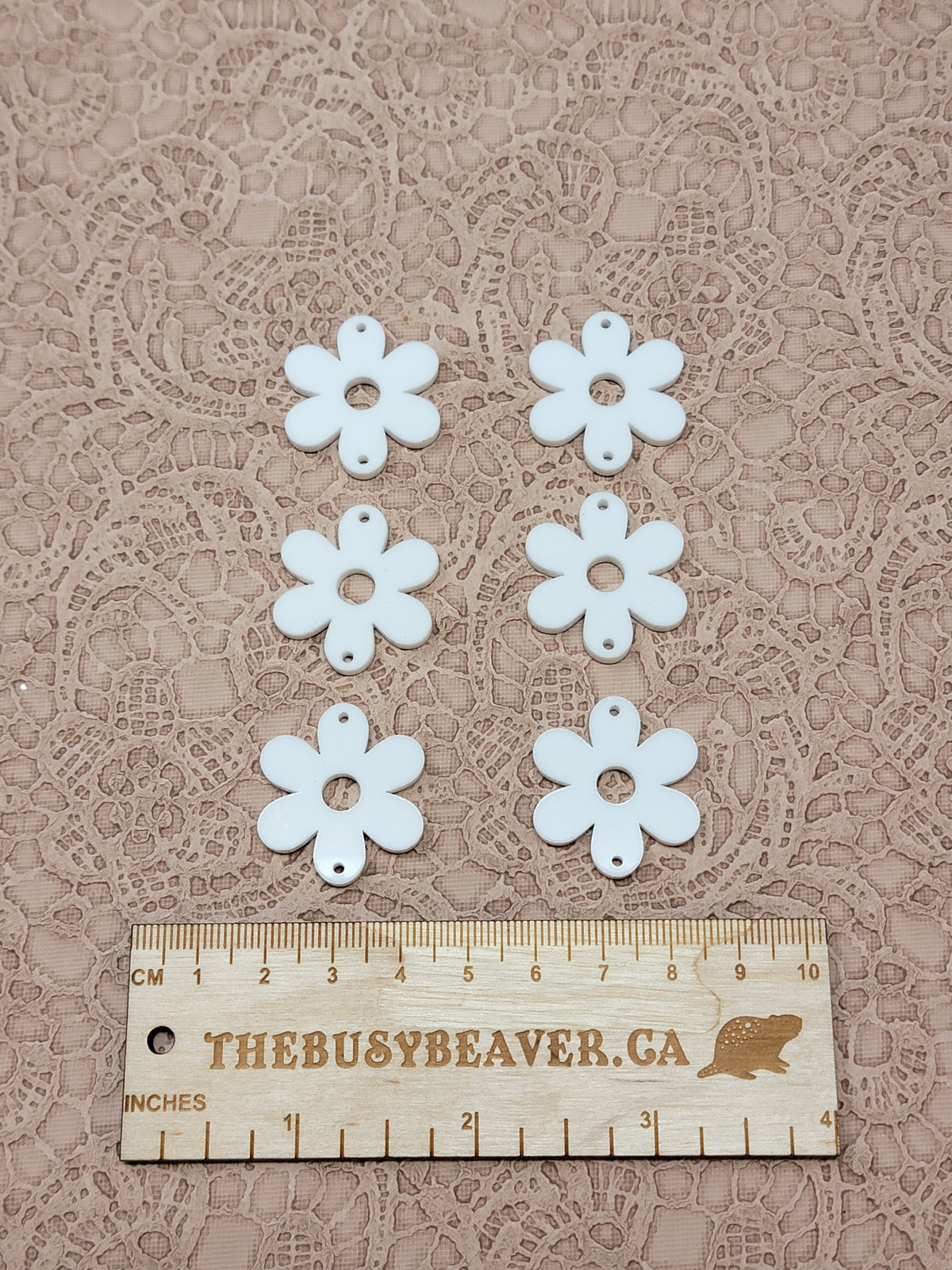 Two sets of three graduated acrylic flower pieces in white, beside a ruler