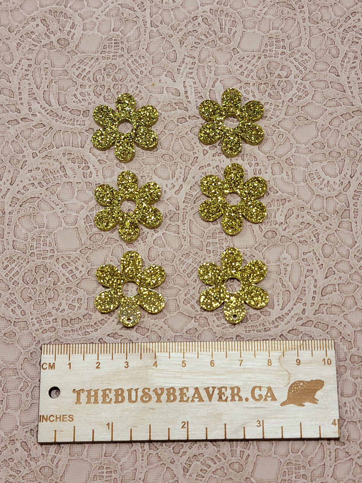 Two sets of three graduated acrylic flower pieces in gold glitter, beside a ruler