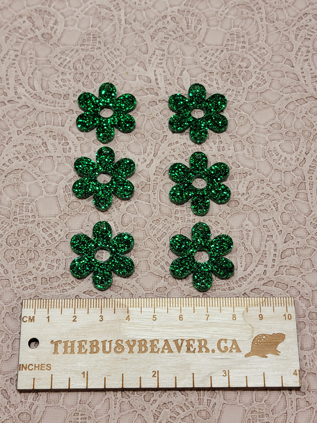 Two sets of three graduated acrylic flower pieces in green glitter, beside a ruler