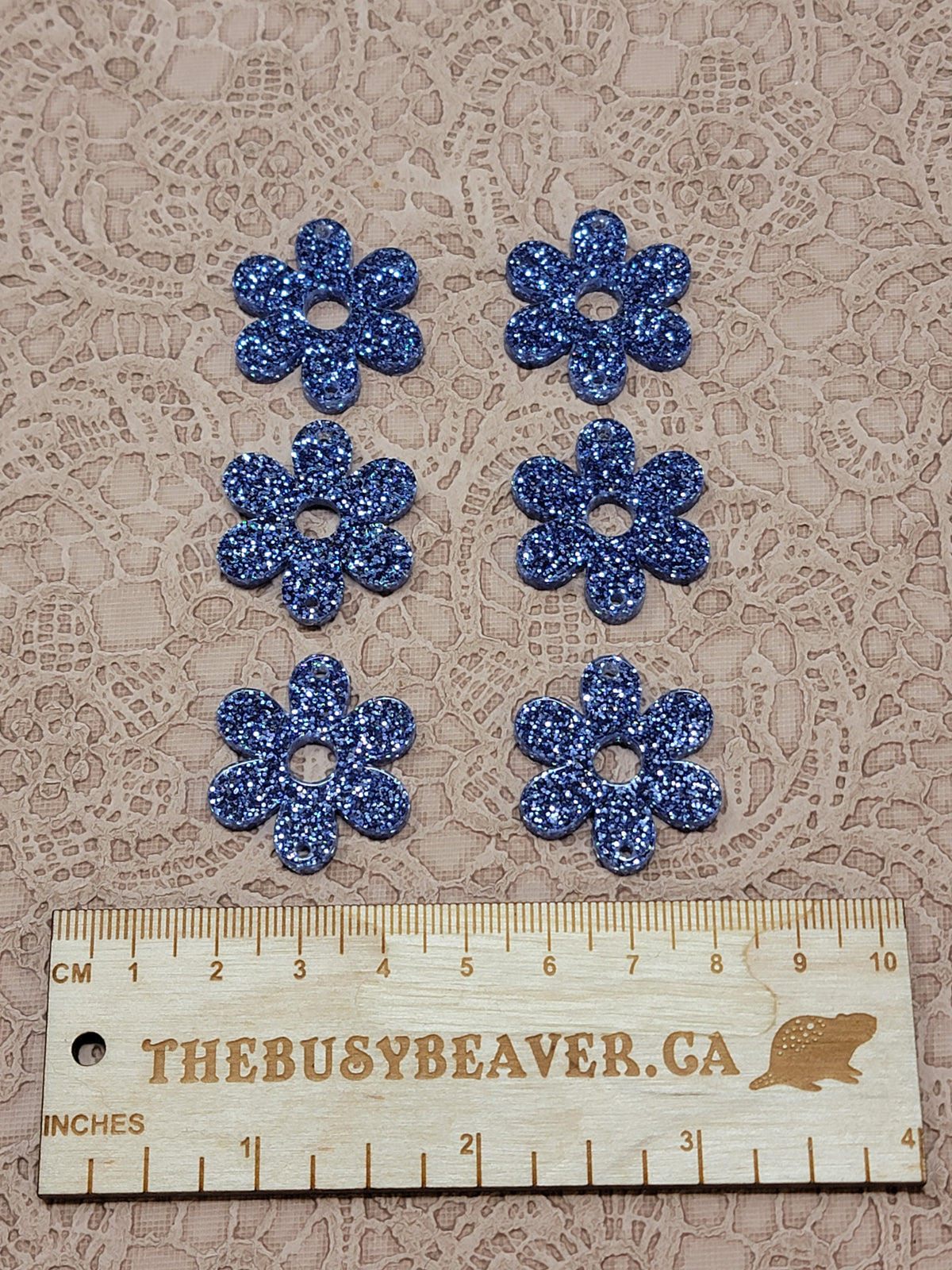Two sets of three graduated acrylic flower pieces in dark blue glitter, beside a ruler