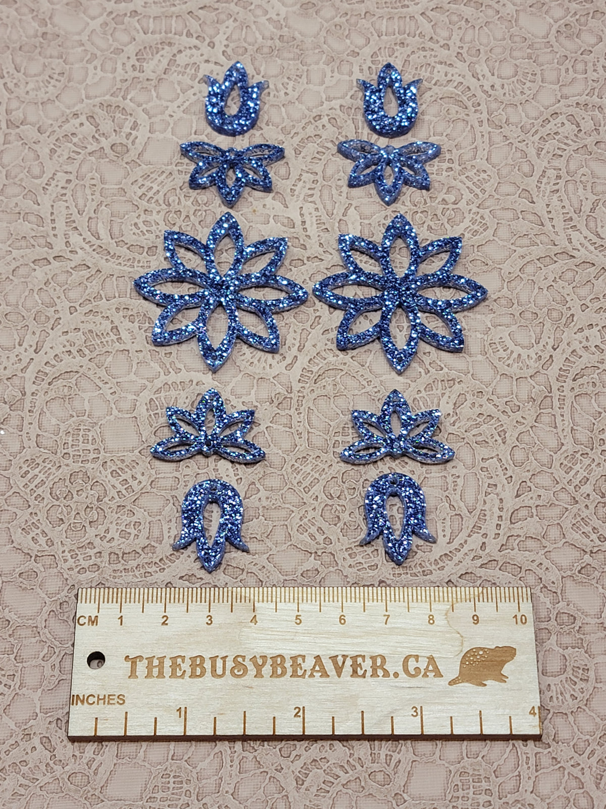 Two 5-tier acrylic flower earring sets in dark blue glitter, laid out top to bottom beside a ruler