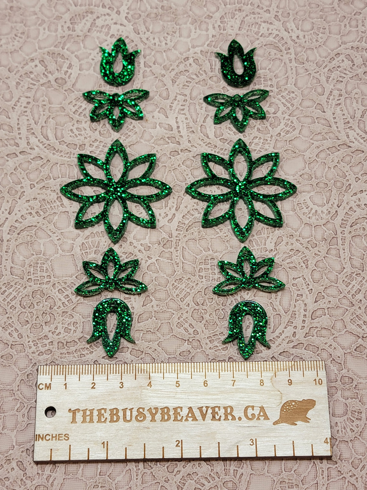 Two 5-tier acrylic flower earring sets in green glitter, laid out top to bottom beside a ruler