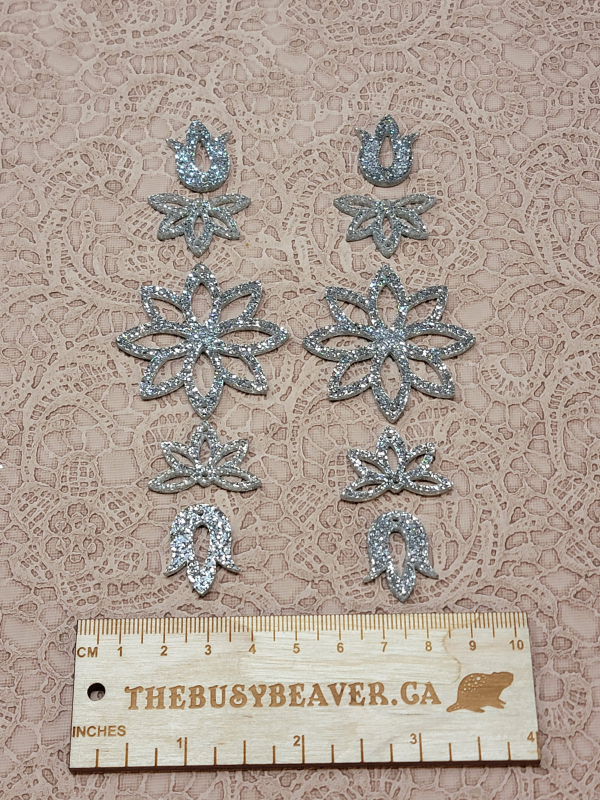Two 5-tier acrylic flower earring sets in silver glitter, laid out top to bottom beside a ruler