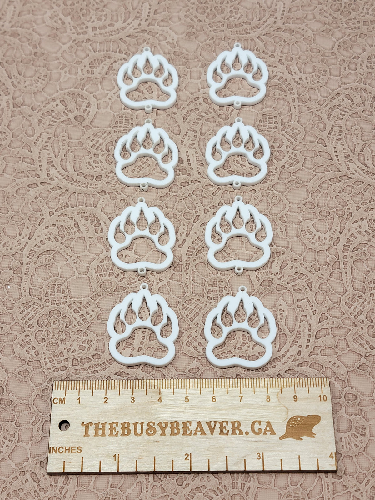 Two sets of four graduated acrylic open bear paws in white, beside a ruler