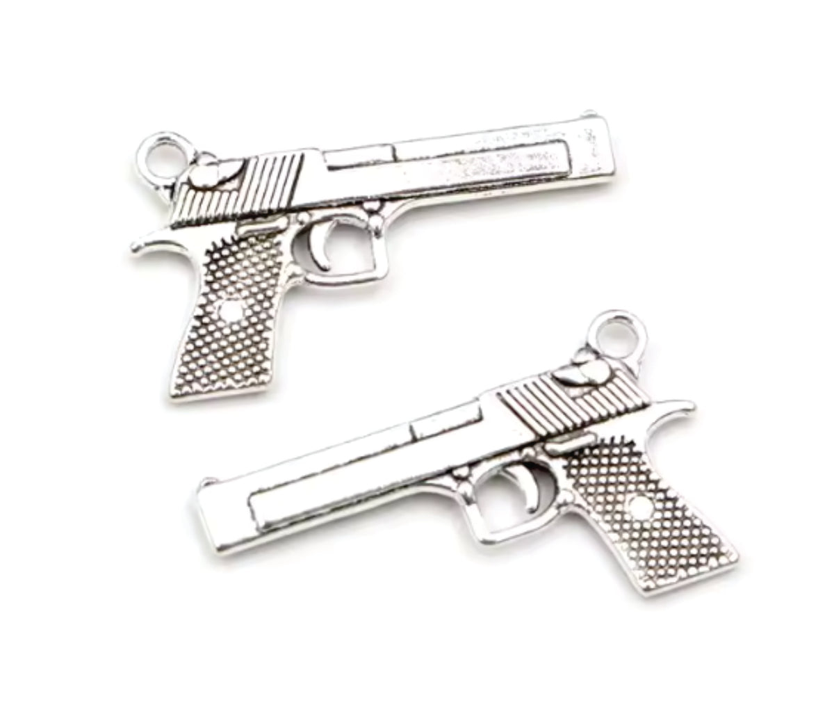 Two silver-tone 34 x 20mm pistol charms with textured grips on a white background