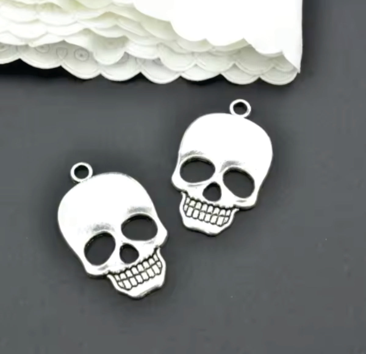Two silver-tone 21 x 36mm skull pendants with flower eye details