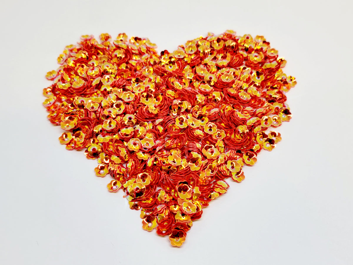 Heart-shaped pile of 6mm iridescent flower sequins in fire red