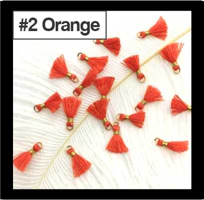Scattered 1cm orange cotton tassels with gold-tone rings on white fur, labelled #2