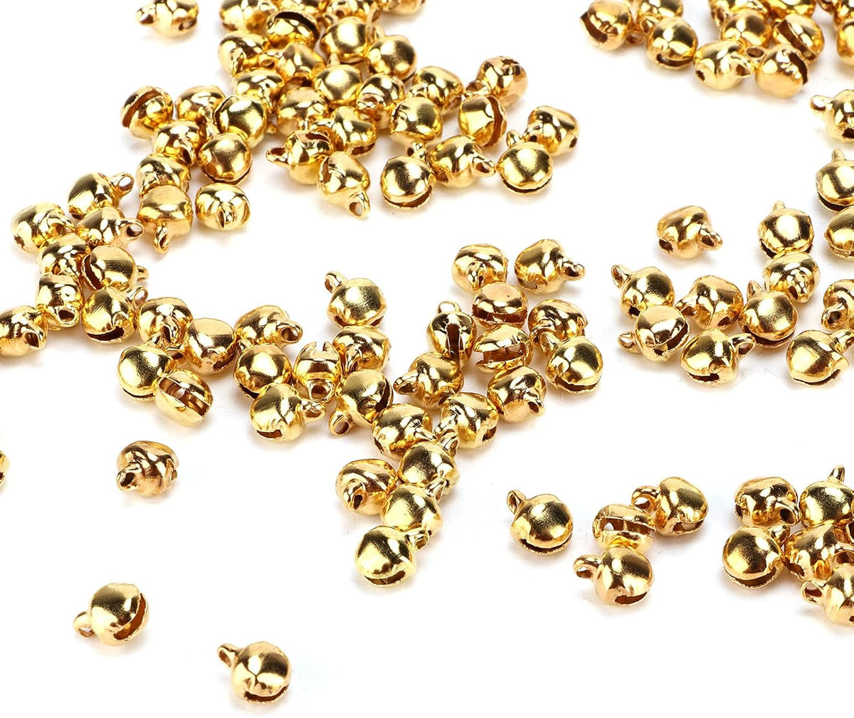 Small gold 6mm metal bells scattered loosely across a white background
