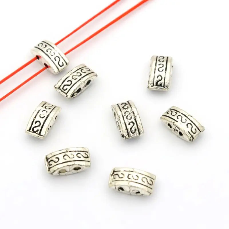 Silver-tone 2-hole metal spacer bars with a patterned edge, seen from above
