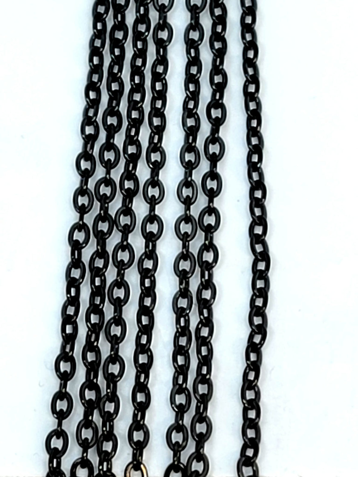Hanging strands of 2mm black stainless steel link chain against a white background