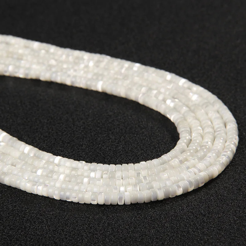 Strands of white 2 x 4mm mother of pearl disc beads laid side by side