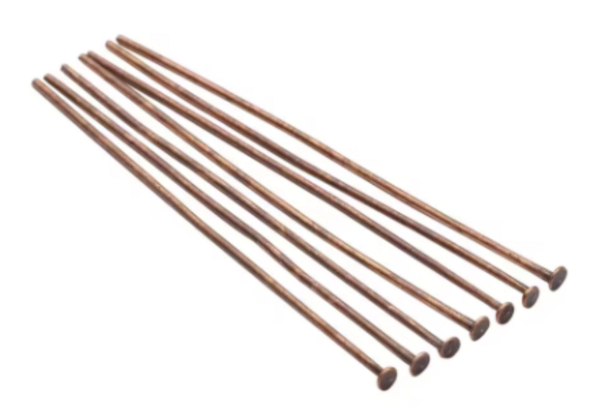 Fan of 30mm copper 20 gauge flat head pins, each with a flat disc head at one end, on white