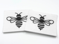 Two beading patterns printed in black on stiff white pellon squares, showing a bold striped bee