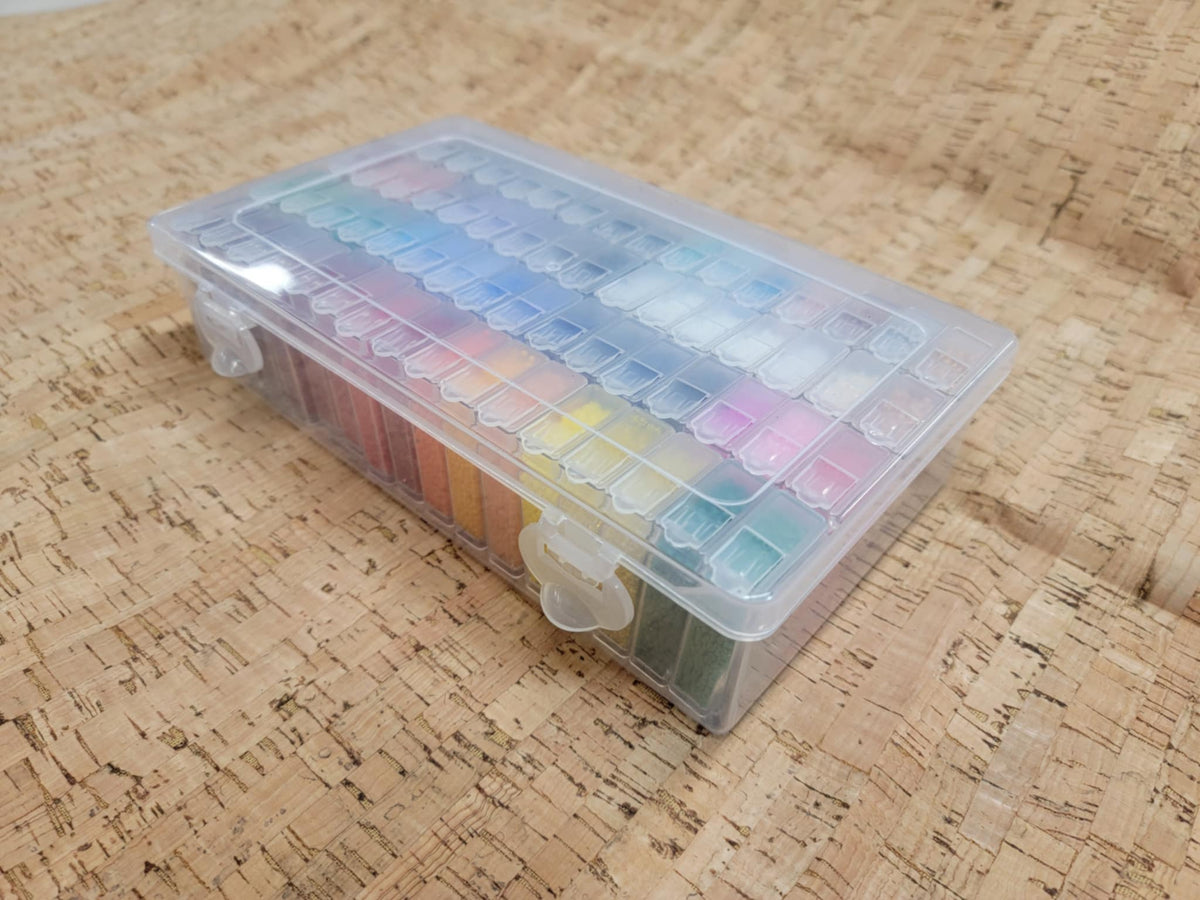 Closed clear variety box packed with tubes of colourful seed beads, seen from an angle