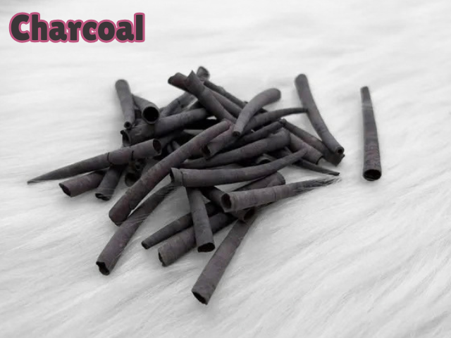 Pile of charcoal dyed smooth dentalium shells, about 1.5 to 2 inches long, on white faux fur
