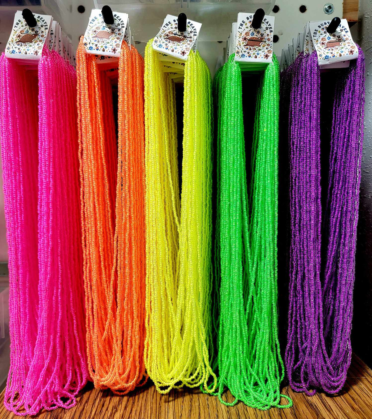 Hanks of Preciosa 11/0 neon seed beads hanging in pink, orange, yellow, green and purple