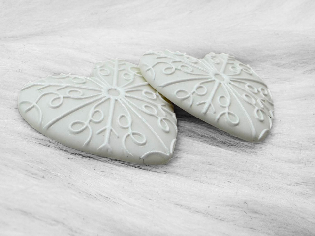 Angled view of the white snowflake Premium 3D heart cabochons showing the raised pattern