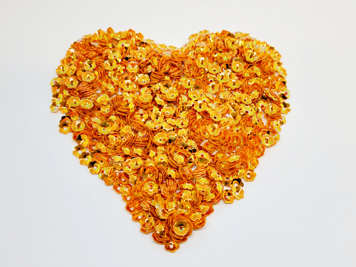 Heart-shaped pile of 6mm iridescent flower sequins in orange
