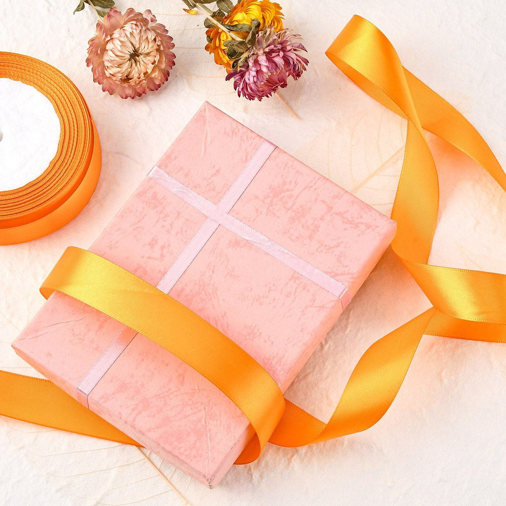 Orange 1-inch satin ribbon wrapped and tied around a pink gift box
