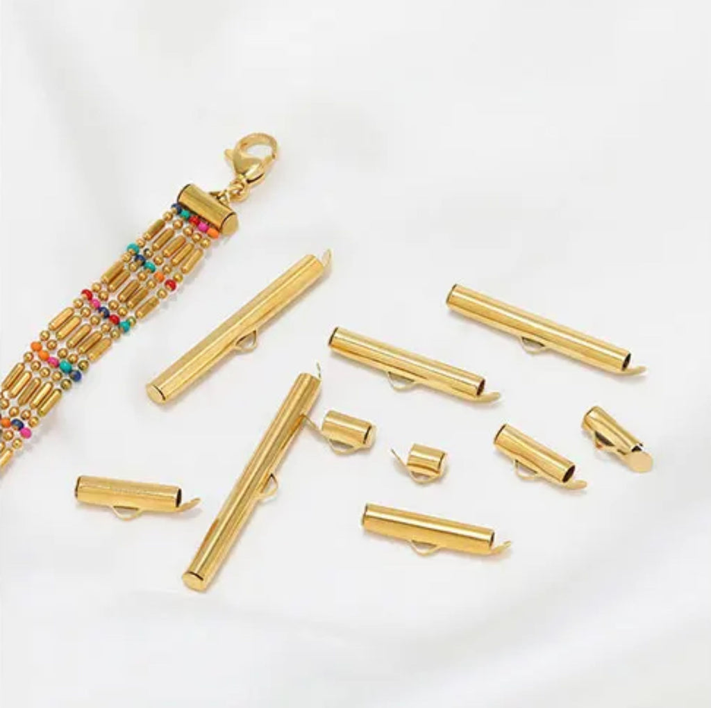 Gold slide-on end clasps in mixed lengths scattered beside a beaded bracelet