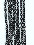 Hanging strands of 3 x 4mm black stainless steel link chain against a white background