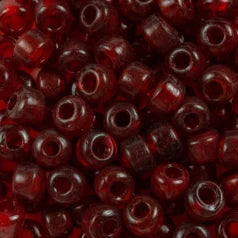 Close-up of 9mm glass crow beads in transparent ruby red, filling the frame