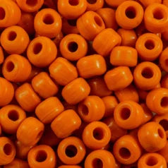 Close-up of 9mm glass crow beads in opaque orange, filling the frame