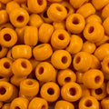 Close-up of 9mm glass crow beads in opaque mustard yellow, filling the frame