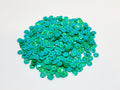 Pile of 6mm round green sequins with centre holes, on a white background
