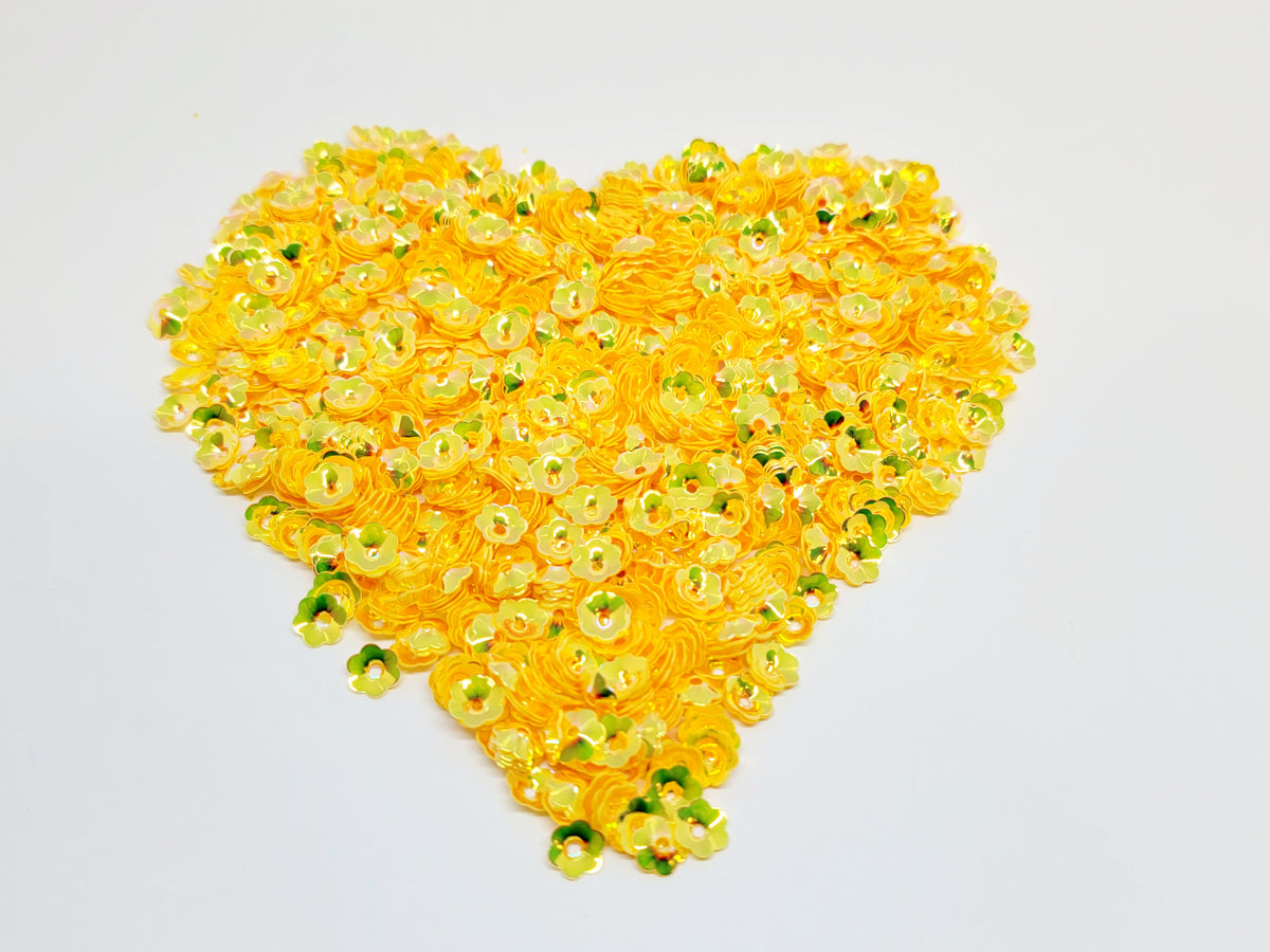 Heart-shaped pile of 6mm iridescent flower sequins in light orange