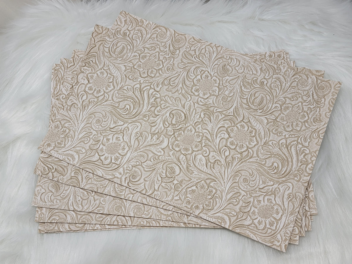 Stack of #50 white faux leather sheets embossed with a tooled floral scroll pattern
