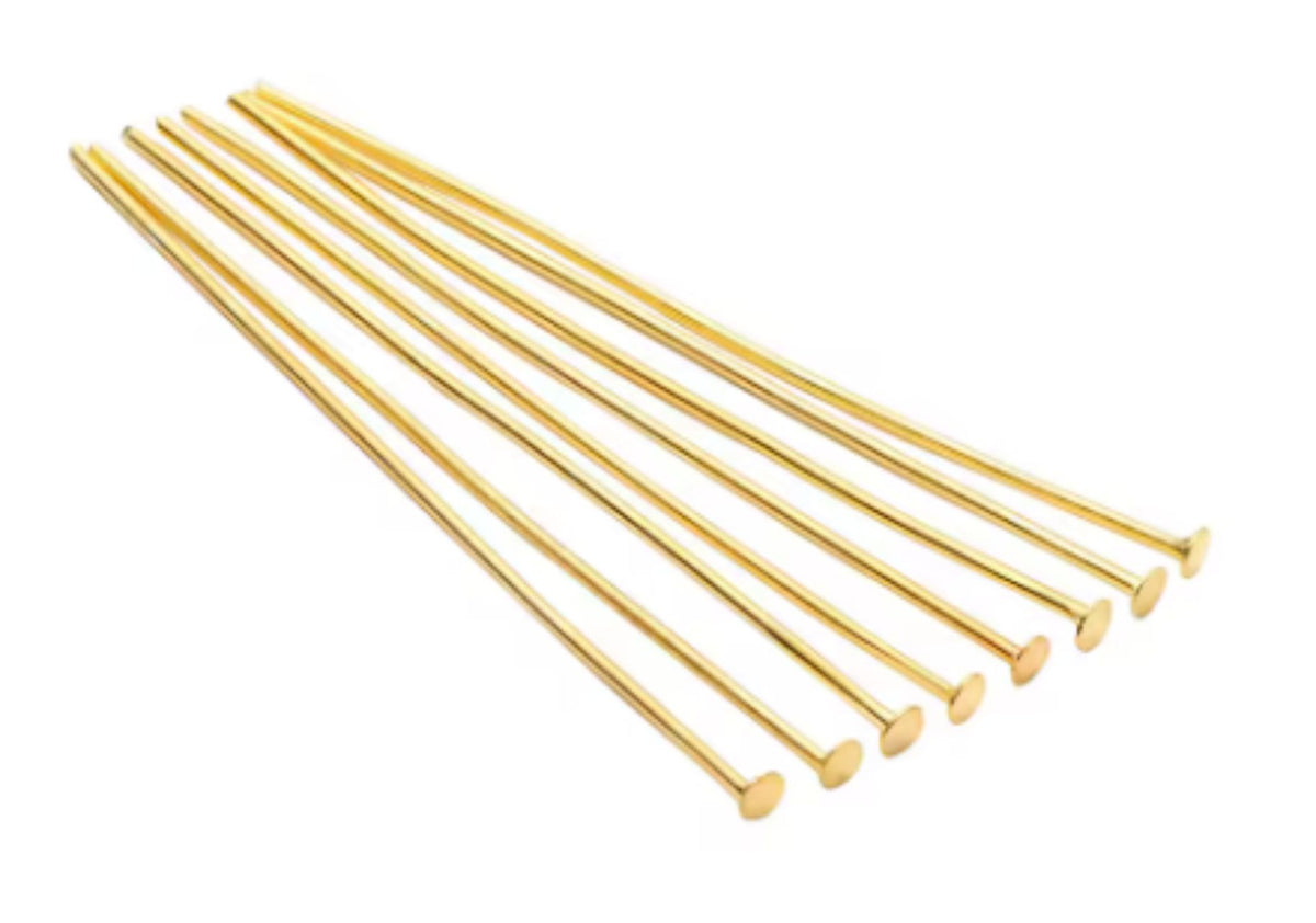 Fan of 50mm gold 20 gauge flat head pins, each with a flat disc head at one end, on white