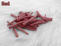 Pile of red dyed smooth dentalium shells, about 1.5 to 2 inches long, on white faux fur