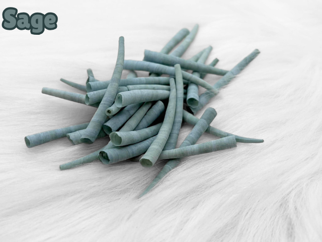 Pile of sage dyed smooth dentalium shells, about 1.5 to 2 inches long, on white faux fur
