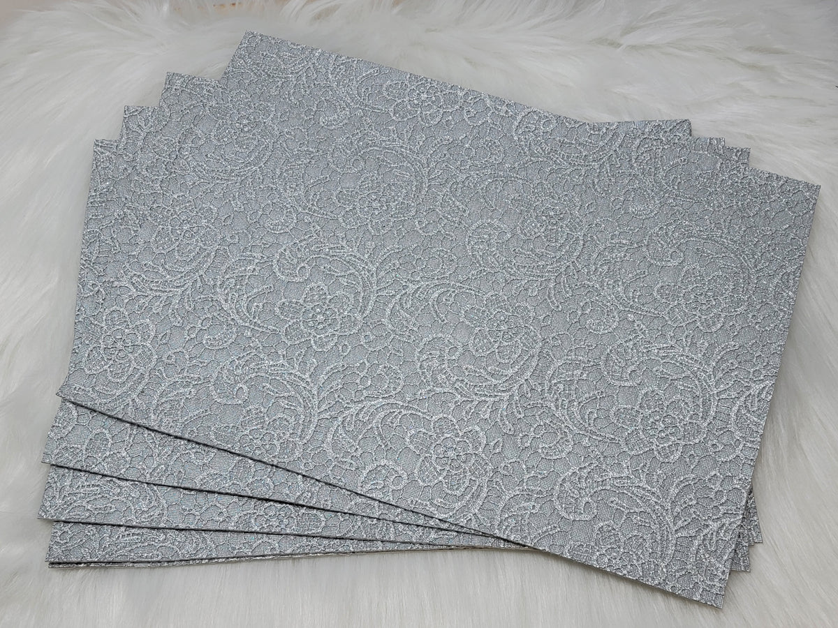 Stack of #58 silver faux leather sheets embossed with a tooled floral scroll pattern